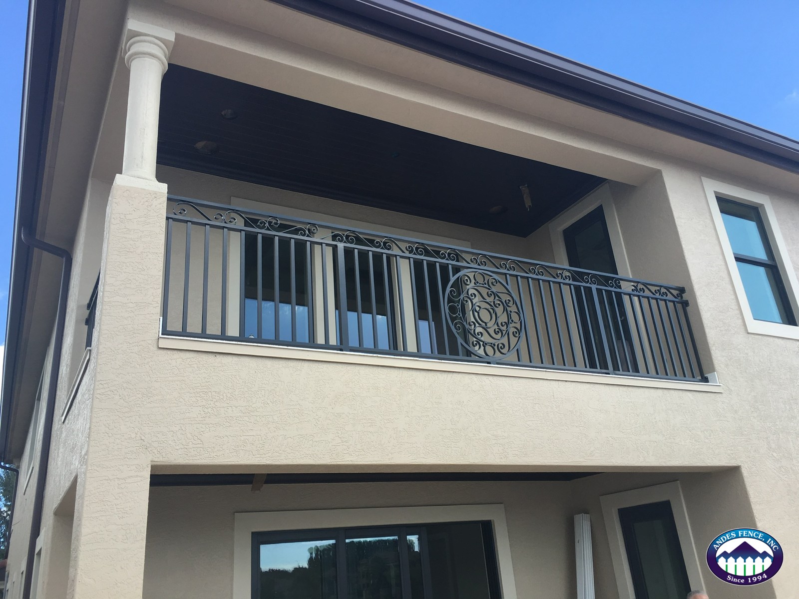 Decorative gray balcony railing with vertical pickets and a circular center detail on an Andes Fence project.
