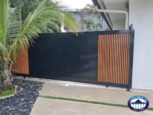 Black sliding gate with wood-look aluminum accents by Andes Fence