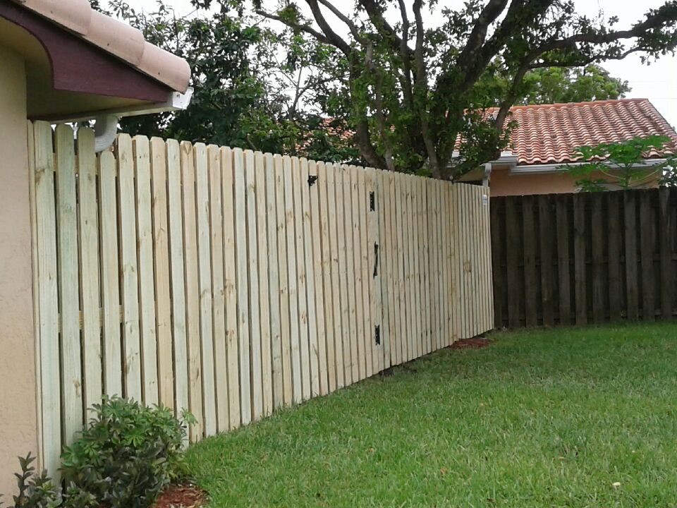 Vertical wood privacy fence with a matching pedestrian gate and black hardware, completed by Andes Fence.